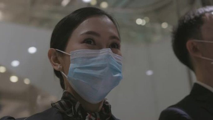 带防护面罩的女乘务员从航站楼的玻璃电梯看风景-库存视频