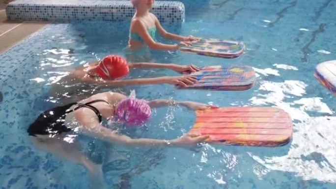 戴着游泳帽和眼镜的小孩在儿童游泳池学习游泳