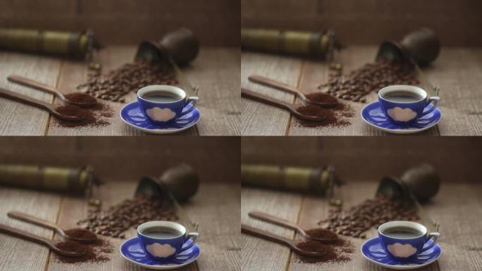 咖啡豆和咖啡粉在棕色背景上的木勺中。配有咖啡壶、蓝色咖啡杯和咖啡研磨机。