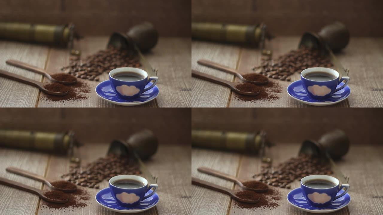 咖啡豆和咖啡粉在棕色背景上的木勺中。配有咖啡壶、蓝色咖啡杯和咖啡研磨机。