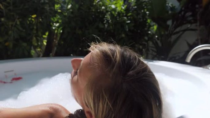 年轻女子在异国情调的户外浴缸中放松。在豪华度假村水疗中心洗澡的女人。
