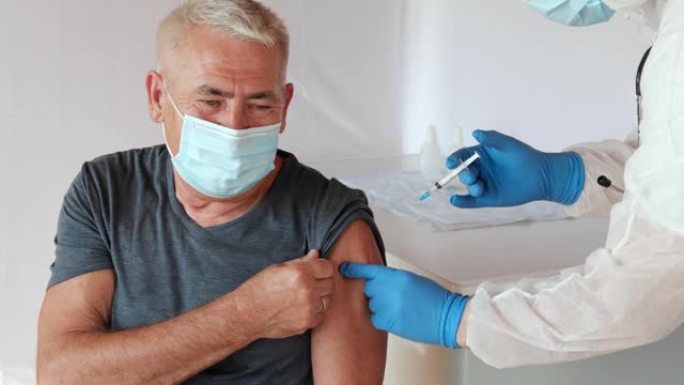 老年人接种疫苗。戴着口罩的老人正在接种疫苗。医生给电晕病毒注射疫苗的病人。新型冠状病毒肺炎流感保护。