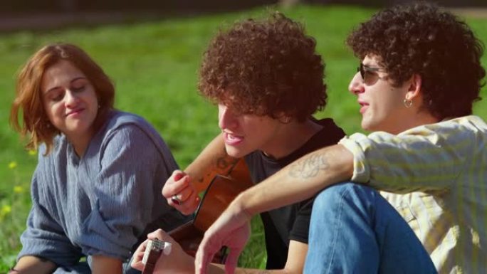 一起唱歌-坐在公园草坪上的年轻朋友一起唱歌