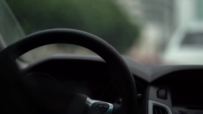 驾驶员在汽车的方向盘后面，手放在方向盘上，视频从车内