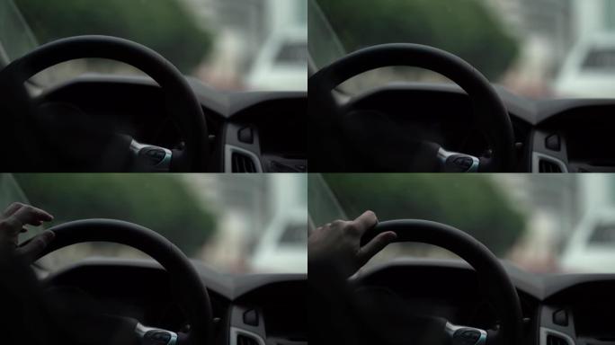 驾驶员在汽车的方向盘后面，手放在方向盘上，视频从车内