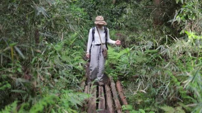 日本妇女在自然界中穿越小木桥