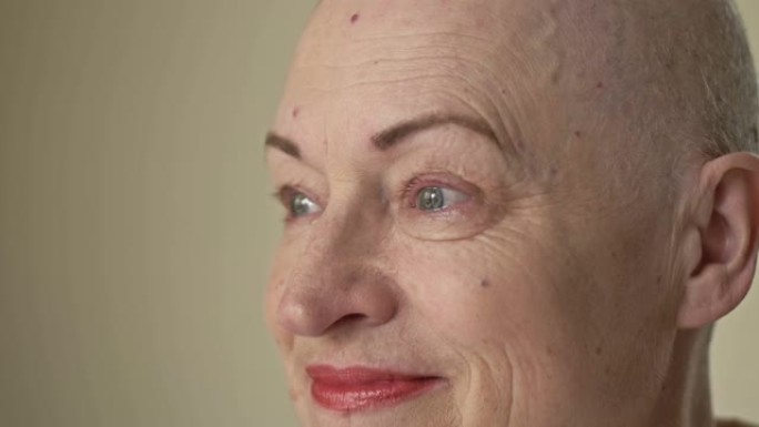 一个患有癌症的女人的脸。她从光头上取下假发。化疗导致脱发。她的眼睛因痛苦，恐惧和绝望而流泪。特写