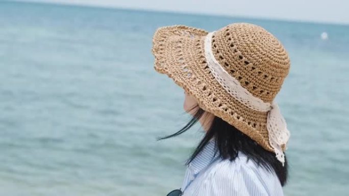 夏天，戴着帽子独自在沙滩上行走的女性旅行者的快乐肖像
