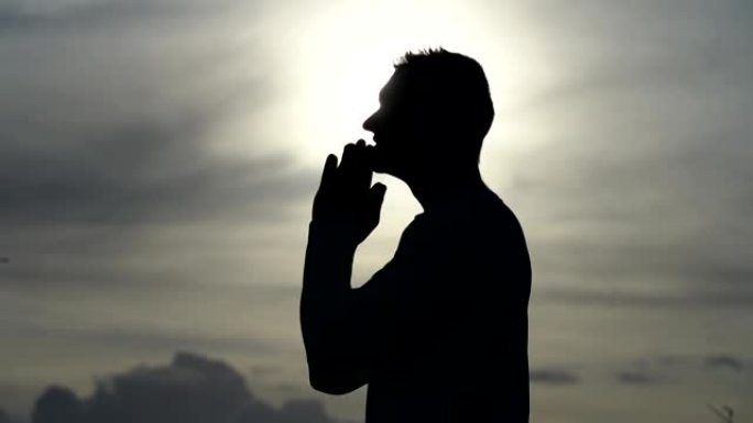 人在日落时祈祷的剪影。宗教、信仰和希望概念