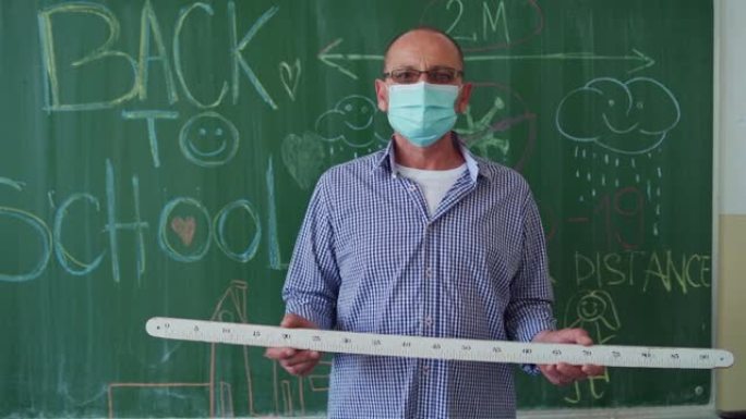 Mathematica老师，在黑板前拿着一把尺子，准备在新型冠状病毒肺炎大流行期间进行第一天的教学