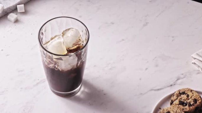 新鲜冲泡的咖啡饮料倒入装有冰块的玻璃杯中。