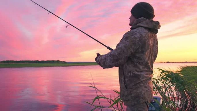 日落时钓鱼的人。日落时在平静的湖上钓鱼的业余垂钓者