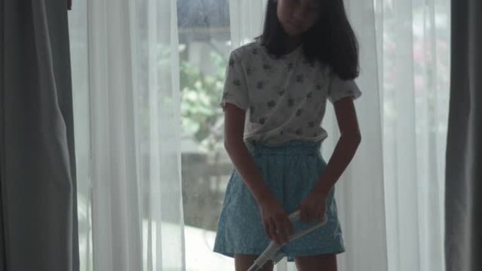 亚洲女孩在家使用吸尘器清洁窗户附近，生活方式理念。