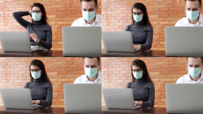 商人和女商人在咖啡店工作时戴着口罩保护病毒，随身携带笔记本电脑，保持社交距离