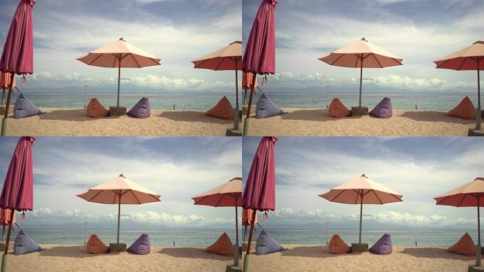 风景美丽宁静的海滩风景，地平线上有海，微风轻拂在沙滩上的太阳伞上。暑假旅行和热带旅游目的地概念