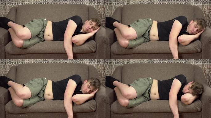胖胖的年轻人睡在沙发上。男人的大肚子。在检疫中增加了多余的体重。