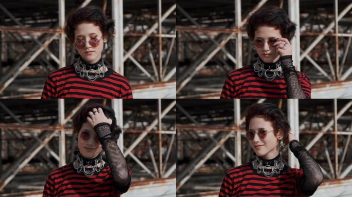 肖像亚洲哥特女孩青少年拉直太阳镜和头发配件在她的脖子上，站在一个旧的废弃建筑的背景。抗议。在青年替代