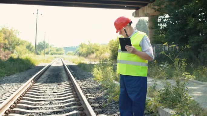 检查导轨的适用性时，穿着制服的高级铁路人员使用平板电脑
