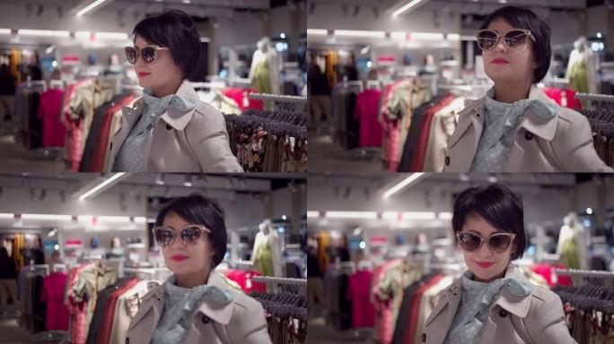 在一家服装店里，一个戴着墨镜的女商人的肖像，看着相机，微笑着，慢动作