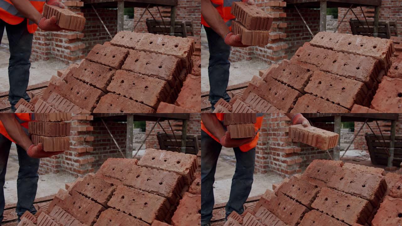 男工人建筑商在建筑工地上手里拿着一块砖。