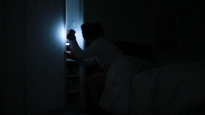 女人在床上的黑暗中发光，女孩在半夜醒来，用手电筒在壁橱里寻找东西