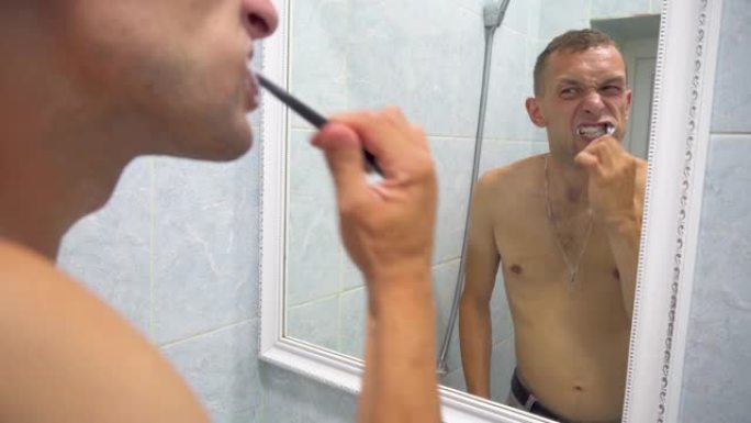 男子刷牙准备早上做卫生程序在家庭浴室的镜子里用牙刷清洁牙齿口腔护理。