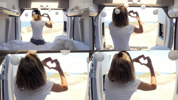 年轻的时髦女子乘坐露营车旅行，制作心形指架