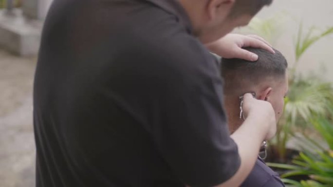 年轻的亚洲男性在家剪头发。