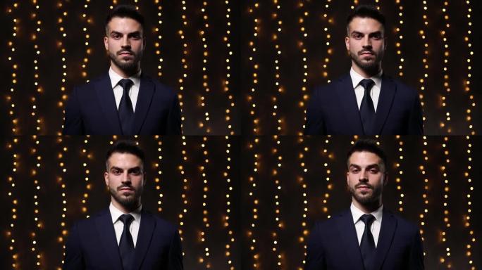 严肃的年轻商人穿着西装思考并同意他的强硬态度，抬头仰望并站在灯光背景上