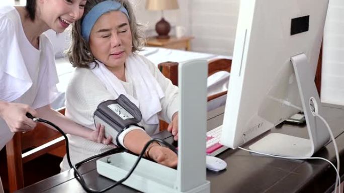 亚洲妇女为她的高级妇女测量血压咨询医生