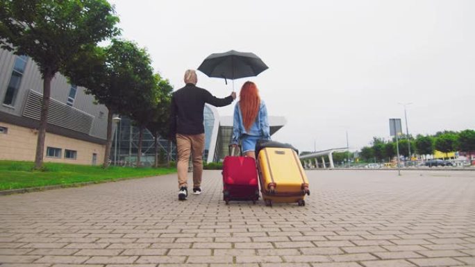 一个女人背着两个手提箱，一个男人拿着雨伞。男人在家庭中的优先地位。一对年轻夫妇的关系问题。