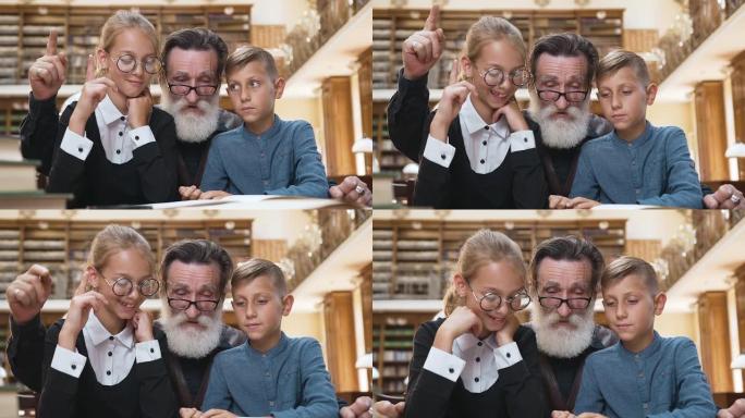 英俊的大胡子老人看书，举起手指，让他十几岁的孙子明白书的内容