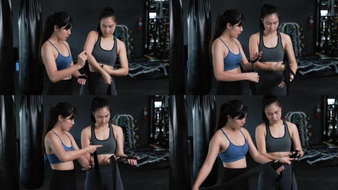 运动年轻的亚洲女性训练拳击手与教练教练一起准备手腕上的绑带，拳击练习运动进行搏击或与健身健身房的伴侣