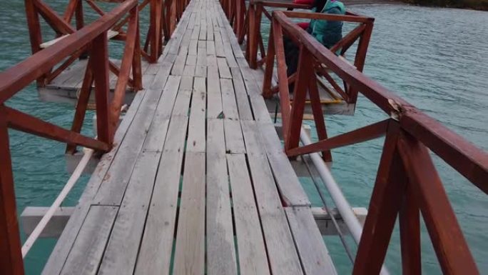 一个男人走过一座桥，一座横跨湖上的桥，一座横跨巴塔哥尼亚湖上的桥