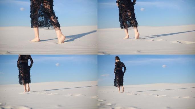 女人的腿赤脚在沙漠中留下的脚印在白沙上。