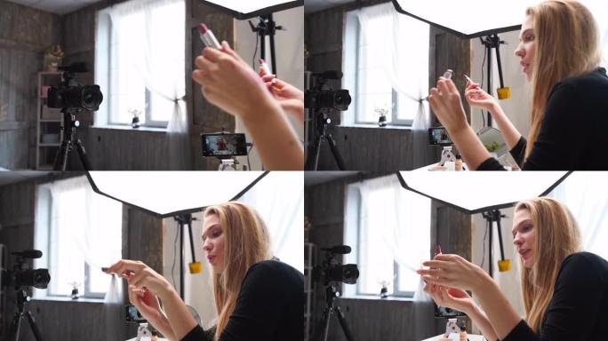 Vlogger女性在嘴唇上涂抹口红。美容博主女人在三脚架上的相机上拍摄日常化妆常规教程。有影响力的金