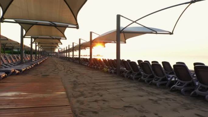 日落时的沙滩日光浴床和雨伞。