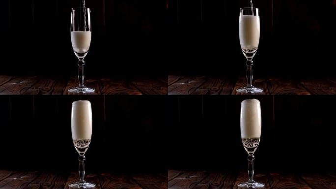 调酒师将香槟倒入黑色背景的玻璃杯中的特写镜头。