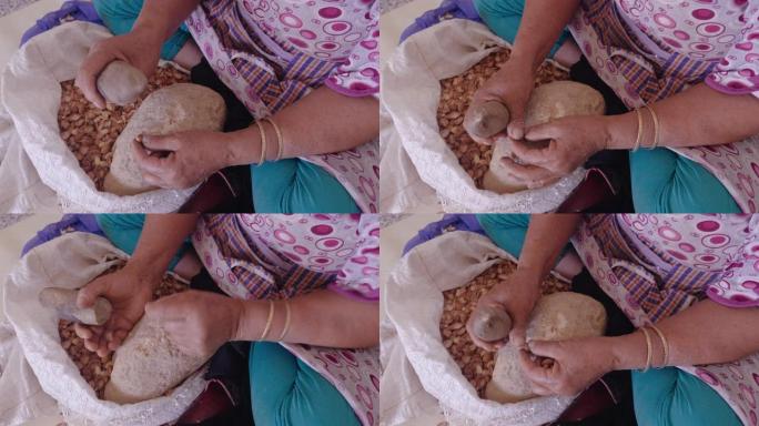 一名摩洛哥妇女打开了摩洛哥坚果的外壳，用于传统的手工摩洛哥坚果油生产。