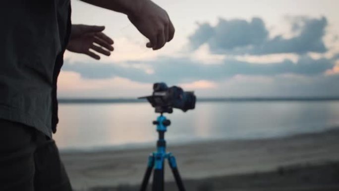 摄影师通过滤光片观察并将其放在固定在三脚架上的相机上，对其进行调整以进行拍摄。河上风景如画的景色