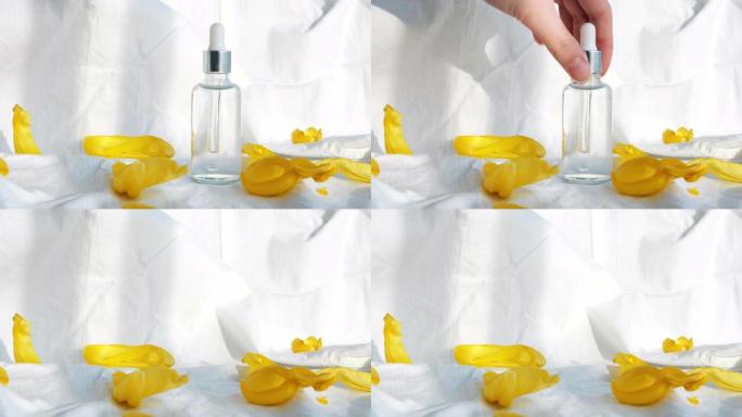 透明玻璃瓶化妆油的特写镜头，白色背景上被黄色郁金香花瓣包围。概念。美容美容，女人手拿走小瓶