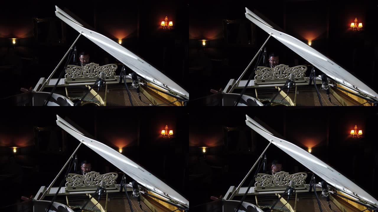钢琴家在观众背景下表演自己的音乐的镜头。透过三角钢琴观看。