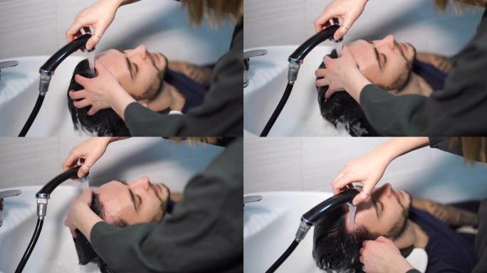 女人涂洗发水按摩头发顾客男人在美容院洗头发。快乐的高加索人享受理发店的服务
