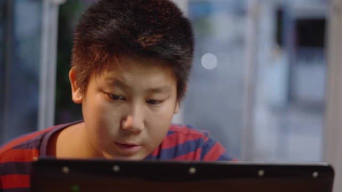 亚洲青春期男孩使用笔记本电脑在家玩网络游戏，生活方式概念。