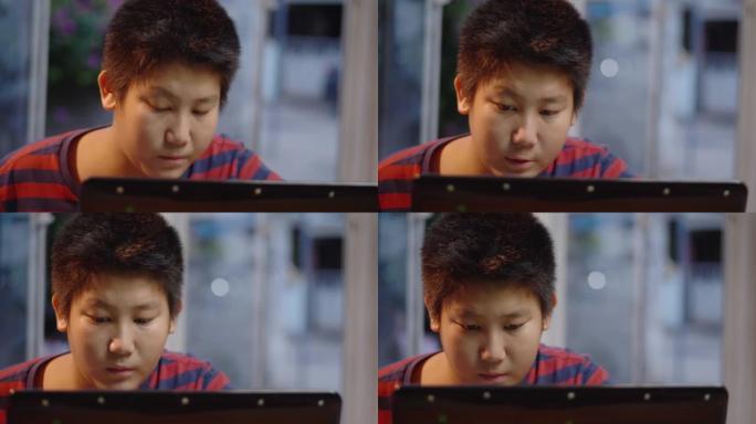 亚洲青春期男孩使用笔记本电脑在家玩网络游戏，生活方式概念。
