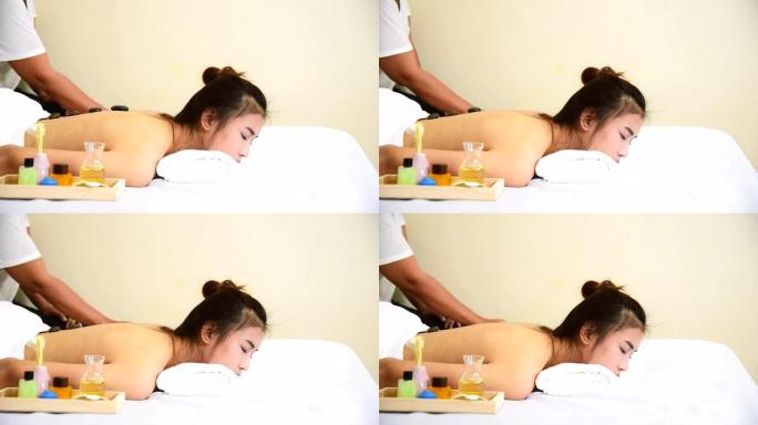 水疗石按摩亚洲美容女性疗法在水疗沙龙放松治疗。年轻民族幸福美女躺在水疗床上护肤有机按摩身体再生。水疗
