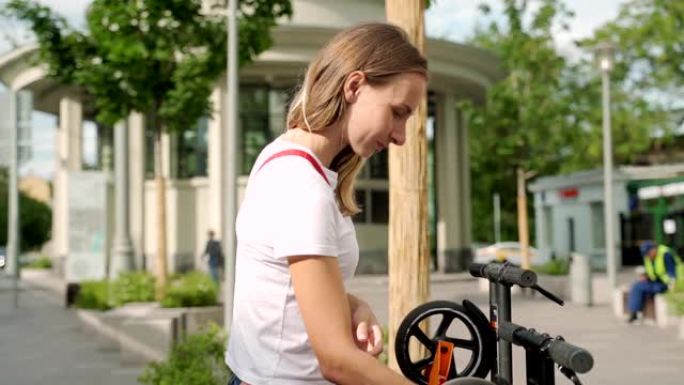 女人站在现代城市街道的停车场上，使用智能手机支付租赁电动踏板车的费用