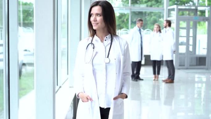 快乐的年轻欧洲女医生穿着白色医用外套和听诊器，看着相机。微笑的女医师在医院办公室摆姿势