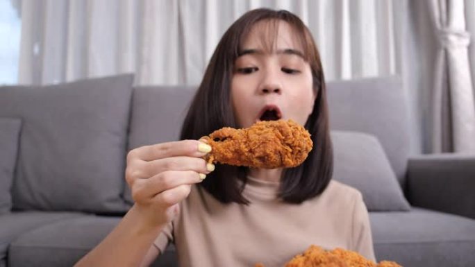 年轻的亚洲女性外卖吃垃圾食品鸡块翅膀，女性玩得开心享受快餐送货服务安全，并通过社交距离概念阻止冠状病