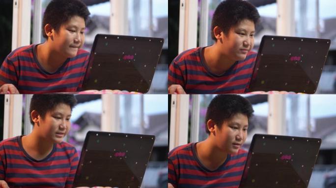 快乐的亚洲男孩在家里玩笔记本电脑在线比赛的游戏，生活方式的概念。